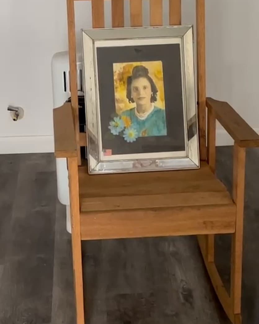 A framed portrait of Josephine Smith resting on a wooden rocking chair in an empty room of the house.